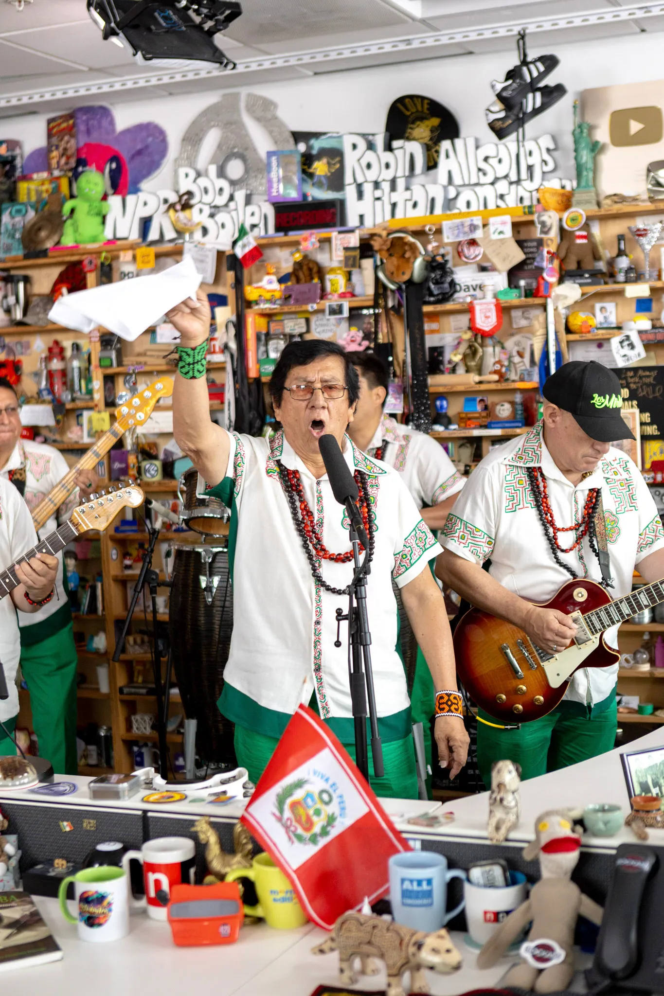 Jorge Rodríguez, founder of Los Mirlos, sings with his arm raised, wearing a shirt embroidered with kené art